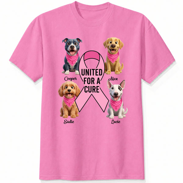 A pink short-sleeve crewneck t-shirt featuring a graphic print of dogs wearing pink bandanas around a large pink ribbon with the text 'UNITED FOR A CURE'.