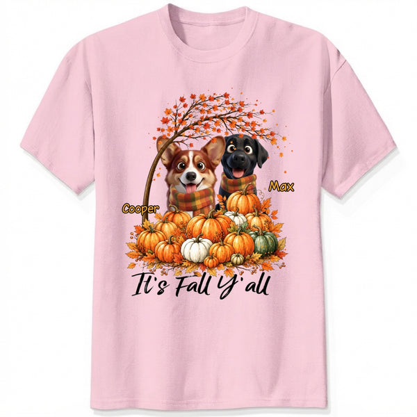A pink short-sleeve crewneck t-shirt featuring a custom autumn graphic of custom dogs sitting on a pile of pumpkins under an orange tree, with the text 'It's Fall Y'all' and custom dog's names