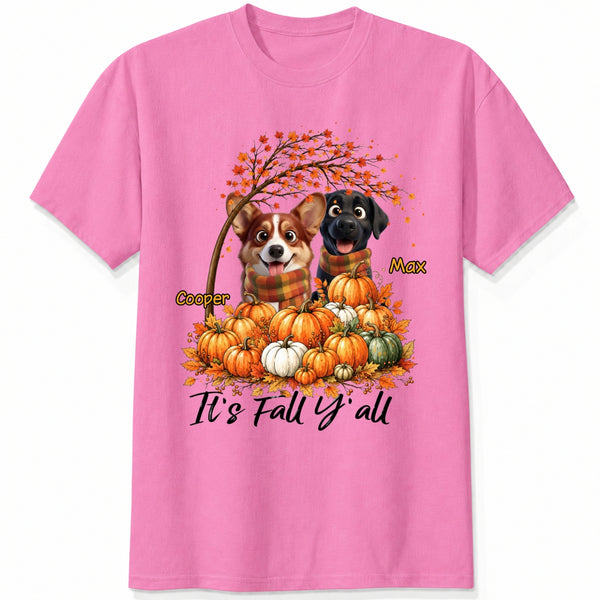 A pink short-sleeve crewneck t-shirt featuring a custom autumn graphic of custom dogs sitting on a pile of pumpkins under an orange tree, with the text 'It's Fall Y'all' and custom dog's names
